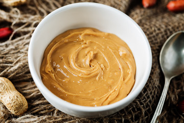 Peanut butter with peanuts on a dark wood background