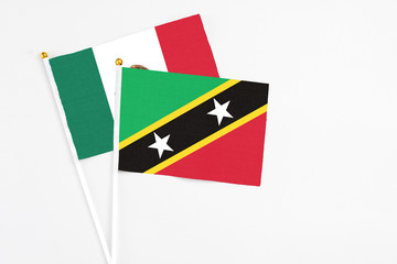 Saint Kitts And Nevis and Mexico stick flags on white background. High quality fabric, miniature national flag. Peaceful global concept.White floor for copy space.