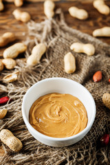 Peanut butter with peanuts on a dark wood background