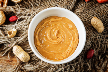 Peanut butter with peanuts on a dark wood background