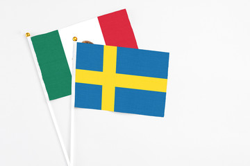 Sweden and Mexico stick flags on white background. High quality fabric, miniature national flag. Peaceful global concept.White floor for copy space.