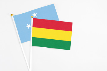 Bolivia and Micronesia stick flags on white background. High quality fabric, miniature national flag. Peaceful global concept.White floor for copy space.