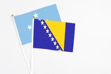 Bosnia Herzegovina and Micronesia stick flags on white background. High quality fabric, miniature national flag. Peaceful global concept.White floor for copy space.