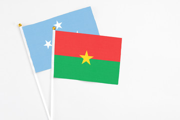 Burkina Faso and Micronesia stick flags on white background. High quality fabric, miniature national flag. Peaceful global concept.White floor for copy space.