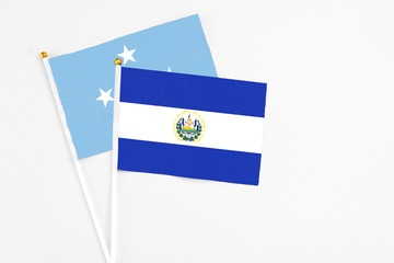 El Salvador and Micronesia stick flags on white background. High quality fabric, miniature national flag. Peaceful global concept.White floor for copy space.