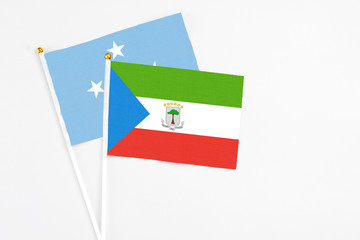 Equatorial Guinea and Micronesia stick flags on white background. High quality fabric, miniature national flag. Peaceful global concept.White floor for copy space.