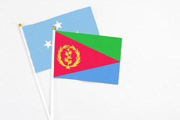 Eritrea and Micronesia stick flags on white background. High quality fabric, miniature national flag. Peaceful global concept.White floor for copy space.