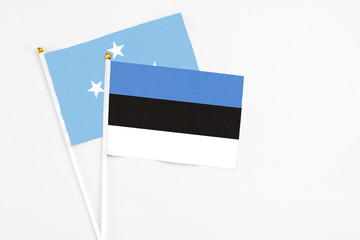 Estonia and Micronesia stick flags on white background. High quality fabric, miniature national flag. Peaceful global concept.White floor for copy space.