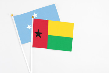 Guinea Bissau and Micronesia stick flags on white background. High quality fabric, miniature national flag. Peaceful global concept.White floor for copy space.