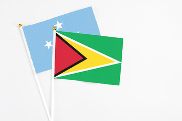 Guyana and Micronesia stick flags on white background. High quality fabric, miniature national flag. Peaceful global concept.White floor for copy space.