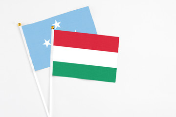 Hungary and Micronesia stick flags on white background. High quality fabric, miniature national flag. Peaceful global concept.White floor for copy space.