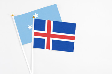 Iceland and Micronesia stick flags on white background. High quality fabric, miniature national flag. Peaceful global concept.White floor for copy space.