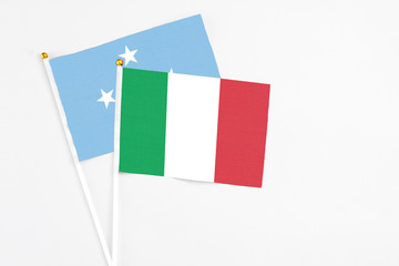 Italy and Micronesia stick flags on white background. High quality fabric, miniature national flag. Peaceful global concept.White floor for copy space.