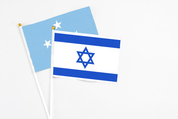 Israel and Micronesia stick flags on white background. High quality fabric, miniature national flag. Peaceful global concept.White floor for copy space.