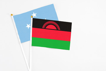 Malawi and Micronesia stick flags on white background. High quality fabric, miniature national flag. Peaceful global concept.White floor for copy space.