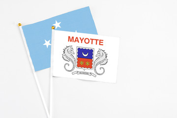 Mayotte and Micronesia stick flags on white background. High quality fabric, miniature national flag. Peaceful global concept.White floor for copy space.