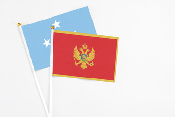Montenegro and Micronesia stick flags on white background. High quality fabric, miniature national flag. Peaceful global concept.White floor for copy space.