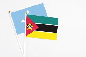 Mozambique and Micronesia stick flags on white background. High quality fabric, miniature national flag. Peaceful global concept.White floor for copy space.