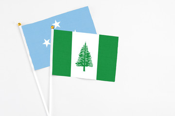 Norfolk Island and Micronesia stick flags on white background. High quality fabric, miniature national flag. Peaceful global concept.White floor for copy space.