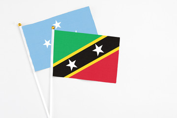 Saint Kitts And Nevis and Micronesia stick flags on white background. High quality fabric, miniature national flag. Peaceful global concept.White floor for copy space.