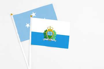 San Marino and Micronesia stick flags on white background. High quality fabric, miniature national flag. Peaceful global concept.White floor for copy space.