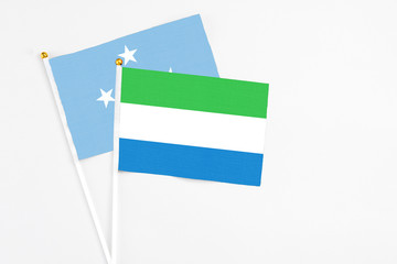 Sierra Leone and Micronesia stick flags on white background. High quality fabric, miniature national flag. Peaceful global concept.White floor for copy space.