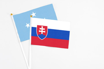 Slovakia and Micronesia stick flags on white background. High quality fabric, miniature national flag. Peaceful global concept.White floor for copy space.