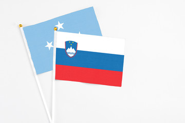Slovenia and Micronesia stick flags on white background. High quality fabric, miniature national flag. Peaceful global concept.White floor for copy space.
