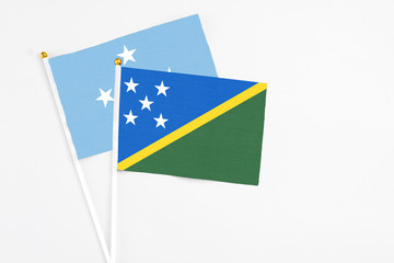 Solomon Islands and Micronesia stick flags on white background. High quality fabric, miniature national flag. Peaceful global concept.White floor for copy space.