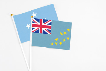 Fototapeta premium Tuvalu and Micronesia stick flags on white background. High quality fabric, miniature national flag. Peaceful global concept.White floor for copy space.