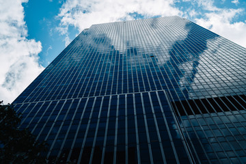Fototapeta na wymiar Crystal exterior with sky reflexion of modern constructed building with corporate offices and company headquarters in financial district, tall skyscraper with luxury apartments located in downtown.