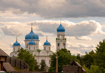 A majestic white temple with blue domes against a cloudy sky.