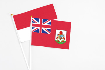 Fototapeta premium Bermuda and Monaco stick flags on white background. High quality fabric, miniature national flag. Peaceful global concept.White floor for copy space.