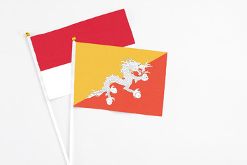 Bhutan and Monaco stick flags on white background. High quality fabric, miniature national flag. Peaceful global concept.White floor for copy space.