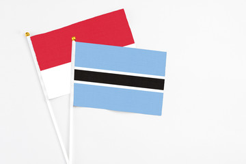 Botswana and Monaco stick flags on white background. High quality fabric, miniature national flag. Peaceful global concept.White floor for copy space.