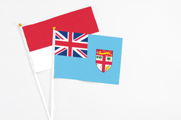 Fiji and Monaco stick flags on white background. High quality fabric, miniature national flag. Peaceful global concept.White floor for copy space.