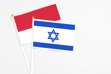 Israel and Monaco stick flags on white background. High quality fabric, miniature national flag. Peaceful global concept.White floor for copy space.