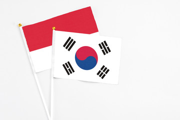 South Korea and Monaco stick flags on white background. High quality fabric, miniature national flag. Peaceful global concept.White floor for copy space.