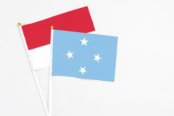 Micronesia and Monaco stick flags on white background. High quality fabric, miniature national flag. Peaceful global concept.White floor for copy space.