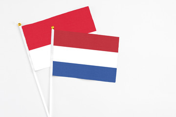 Netherlands and Monaco stick flags on white background. High quality fabric, miniature national flag. Peaceful global concept.White floor for copy space.