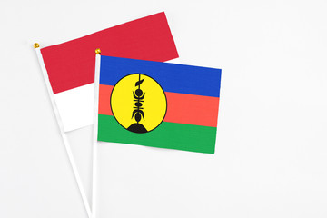 New Caledonia and Monaco stick flags on white background. High quality fabric, miniature national flag. Peaceful global concept.White floor for copy space.