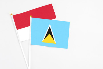 Saint Lucia and Monaco stick flags on white background. High quality fabric, miniature national flag. Peaceful global concept.White floor for copy space.