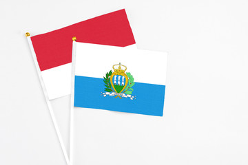 San Marino and Monaco stick flags on white background. High quality fabric, miniature national flag. Peaceful global concept.White floor for copy space.