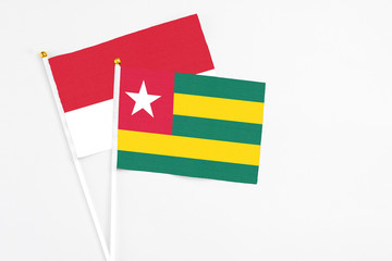Togo and Monaco stick flags on white background. High quality fabric, miniature national flag. Peaceful global concept.White floor for copy space.