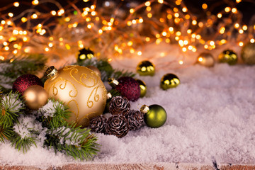 Festive Christmas still life with baubles, ornaments and fir branch in abstract snow landscape with magic lights in background  -  Xmas card  -  Greeting card