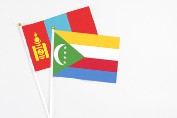 Comoros and Mongolia stick flags on white background. High quality fabric, miniature national flag. Peaceful global concept.White floor for copy space.