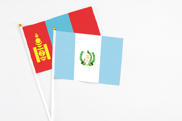 Fototapeta premium Guatemala and Mongolia stick flags on white background. High quality fabric, miniature national flag. Peaceful global concept.White floor for copy space.