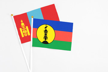 New Caledonia and Mongolia stick flags on white background. High quality fabric, miniature national flag. Peaceful global concept.White floor for copy space.