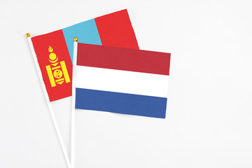 Netherlands and Mongolia stick flags on white background. High quality fabric, miniature national flag. Peaceful global concept.White floor for copy space.