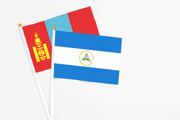 Nicaragua and Mongolia stick flags on white background. High quality fabric, miniature national flag. Peaceful global concept.White floor for copy space.